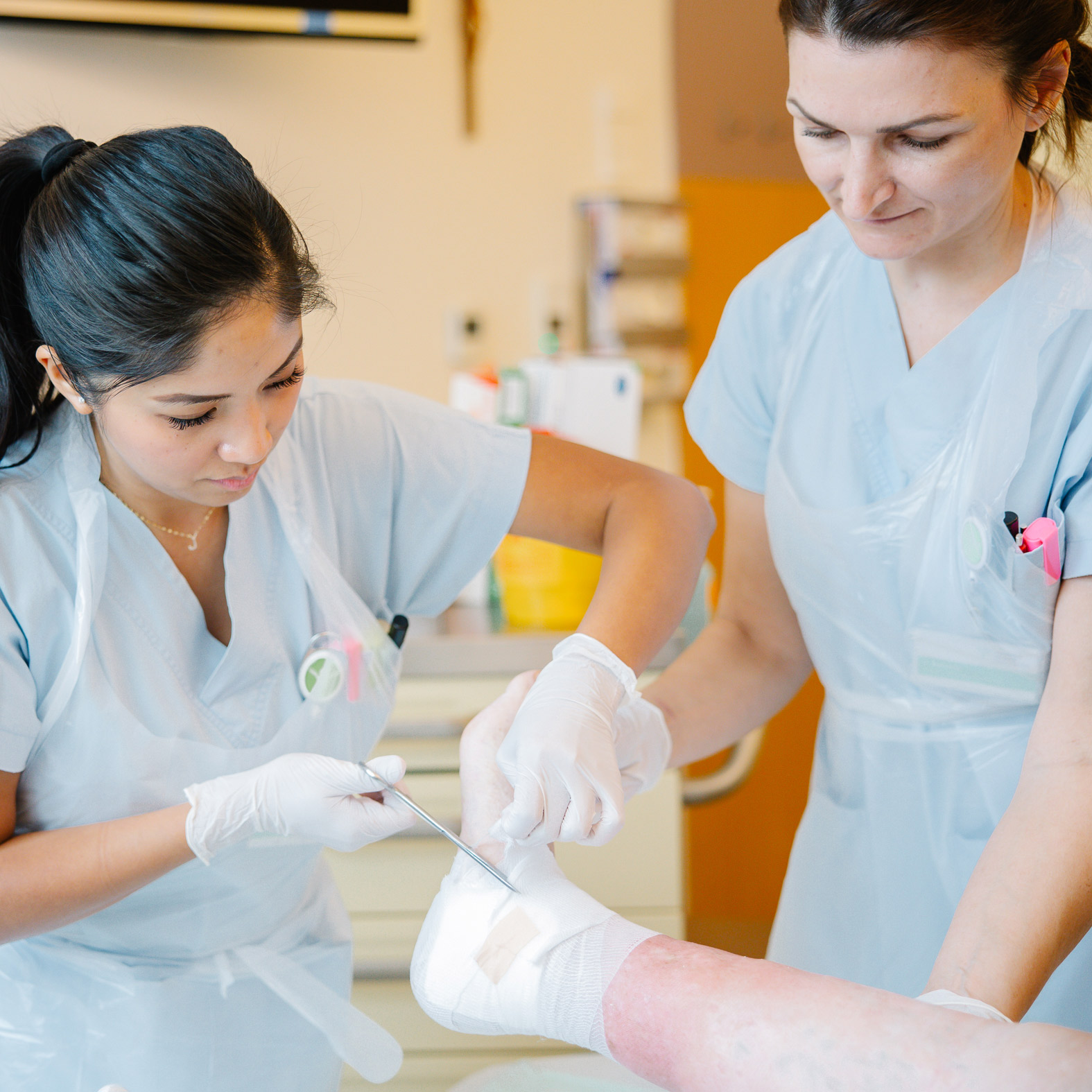 Zwei Frauen versorgen eine Wunde am Fuß einer Patientin