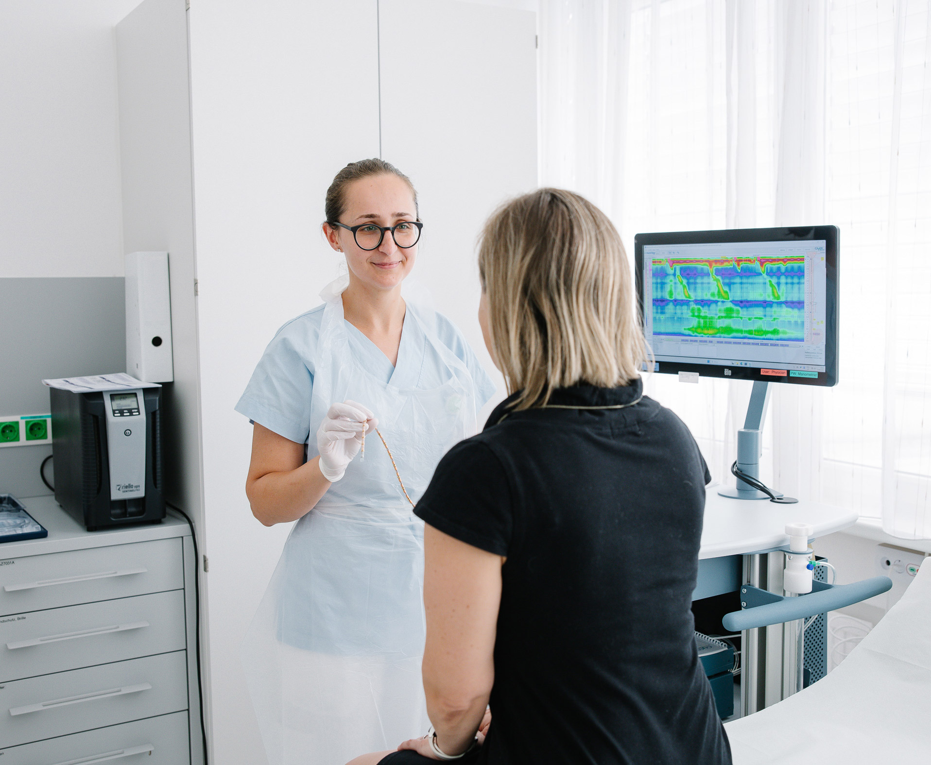 Eine Pflegeperson erklärt einer Patientinden Ablauf einer Untersuchung