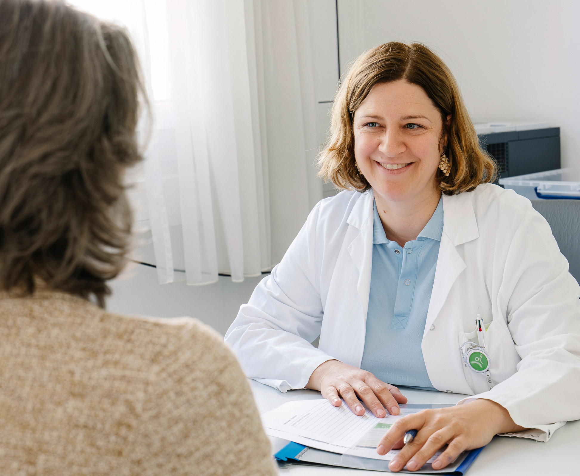 Eine Ärztin mit braunen Haaren beim Aufklärungsgespräch mit einer Patientin
