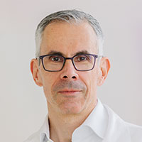 Ein Mann mit grauen kurzen Haaren und Brille