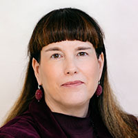 Portraitbild einer Frau mit dunklen langen Haaren und Stirnfransen mit lila Ohrrringen