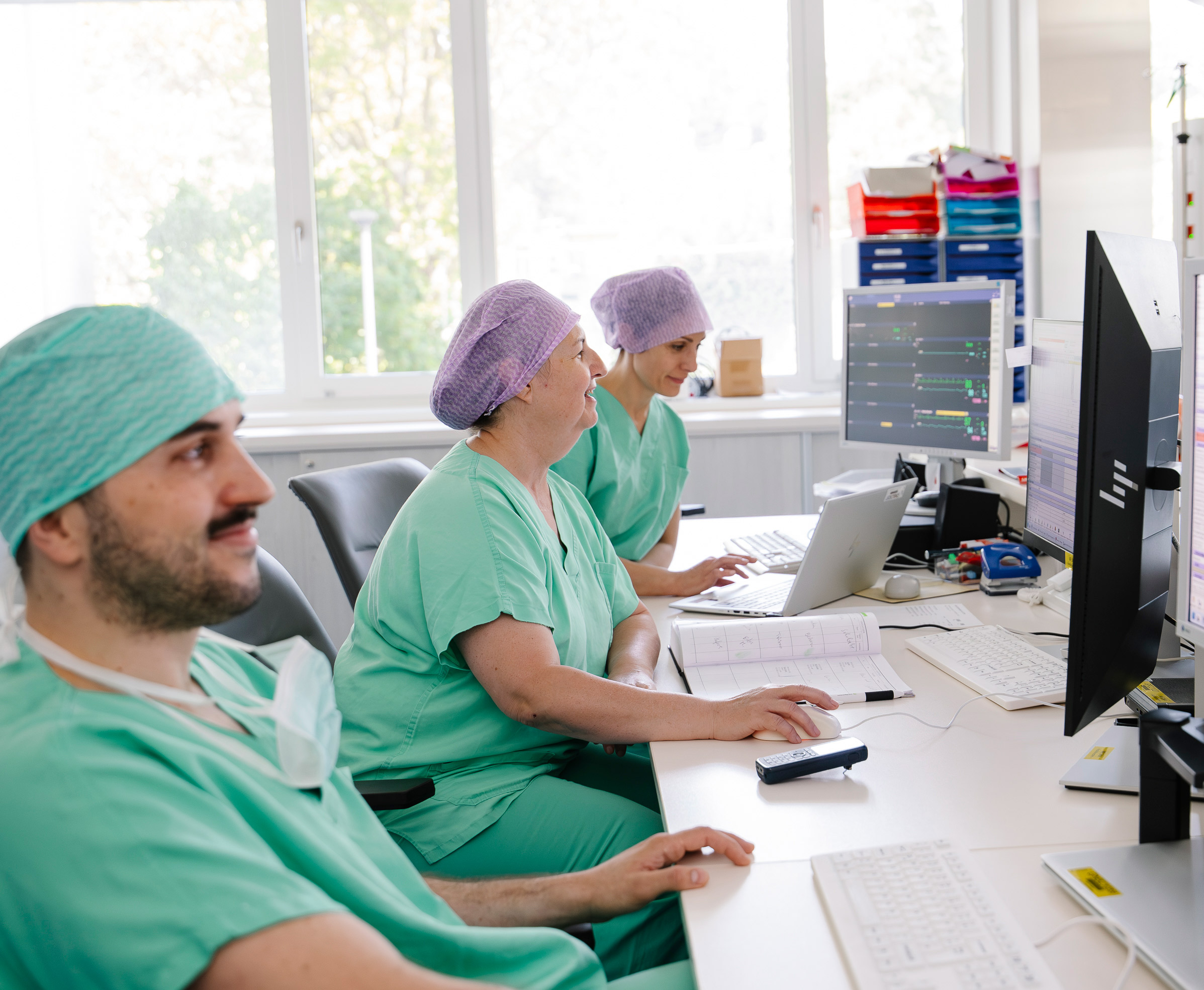 3 Personen kontrollieren die Werte der Patienten an den Bildschirmen