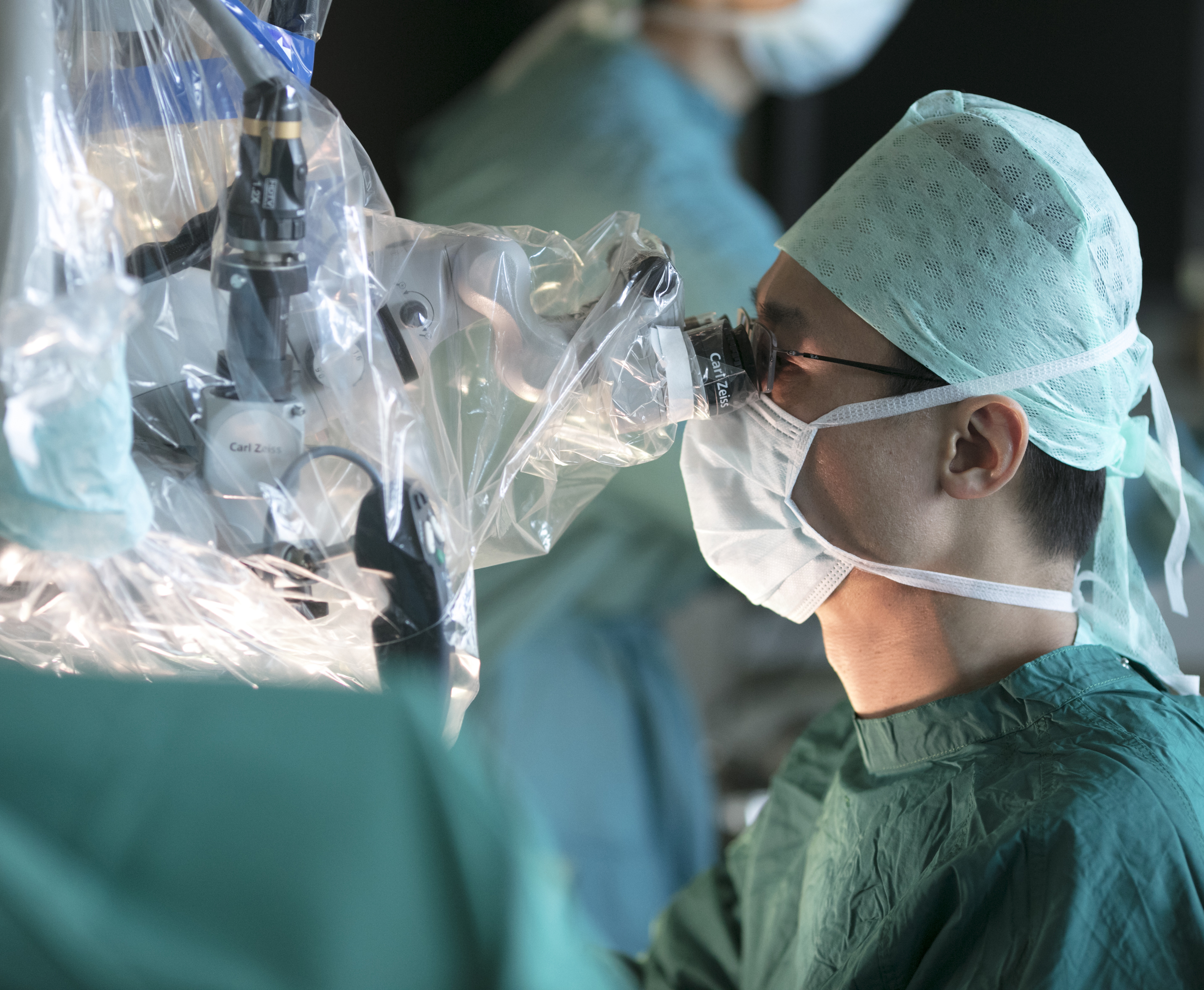 Ein Chirurg blickt durch ein großes chirurgisches Mikroskop während einer Operation.