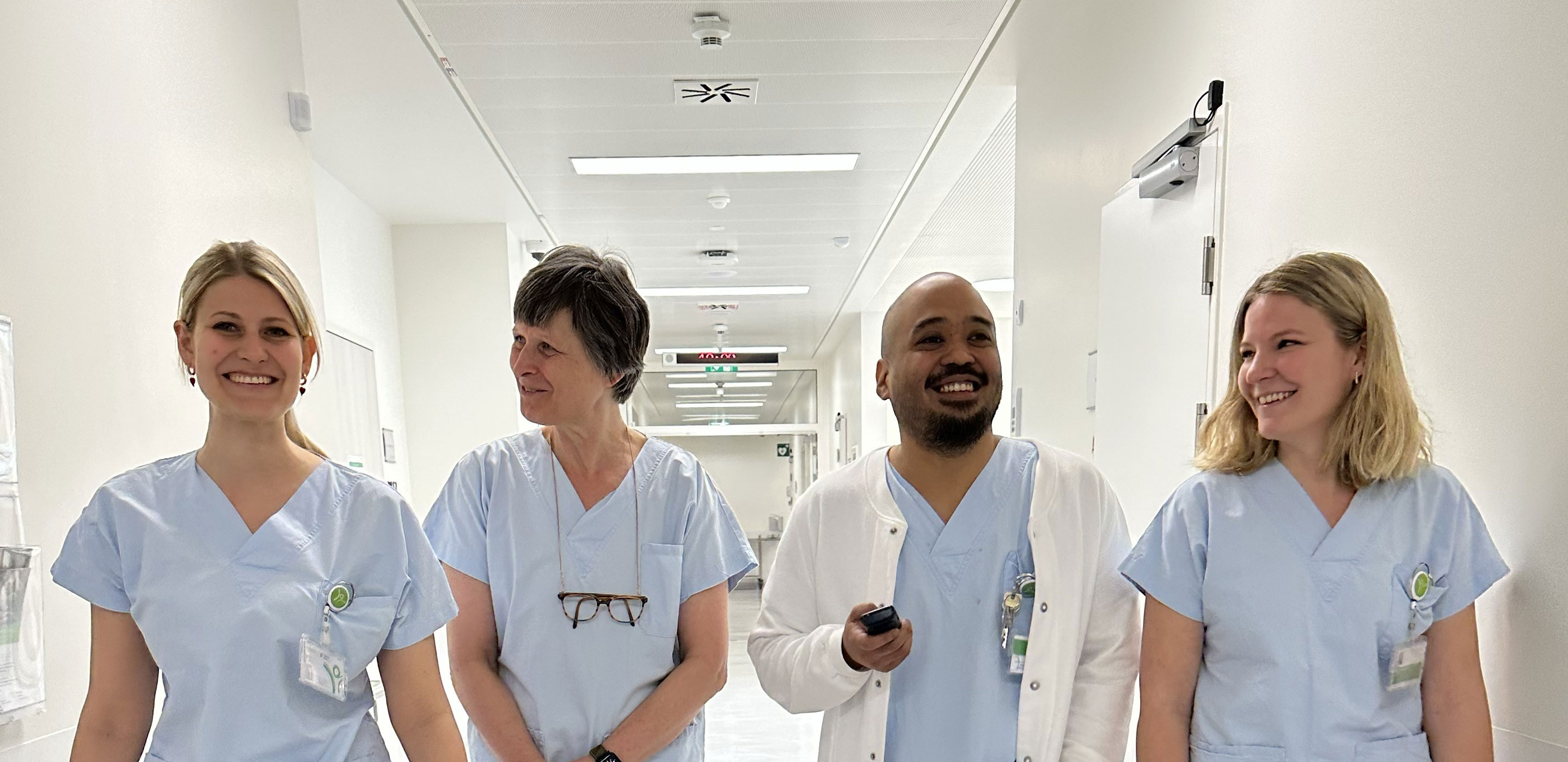 Drei Frauen und ein Mann gehen sich unterhaltend am Gang