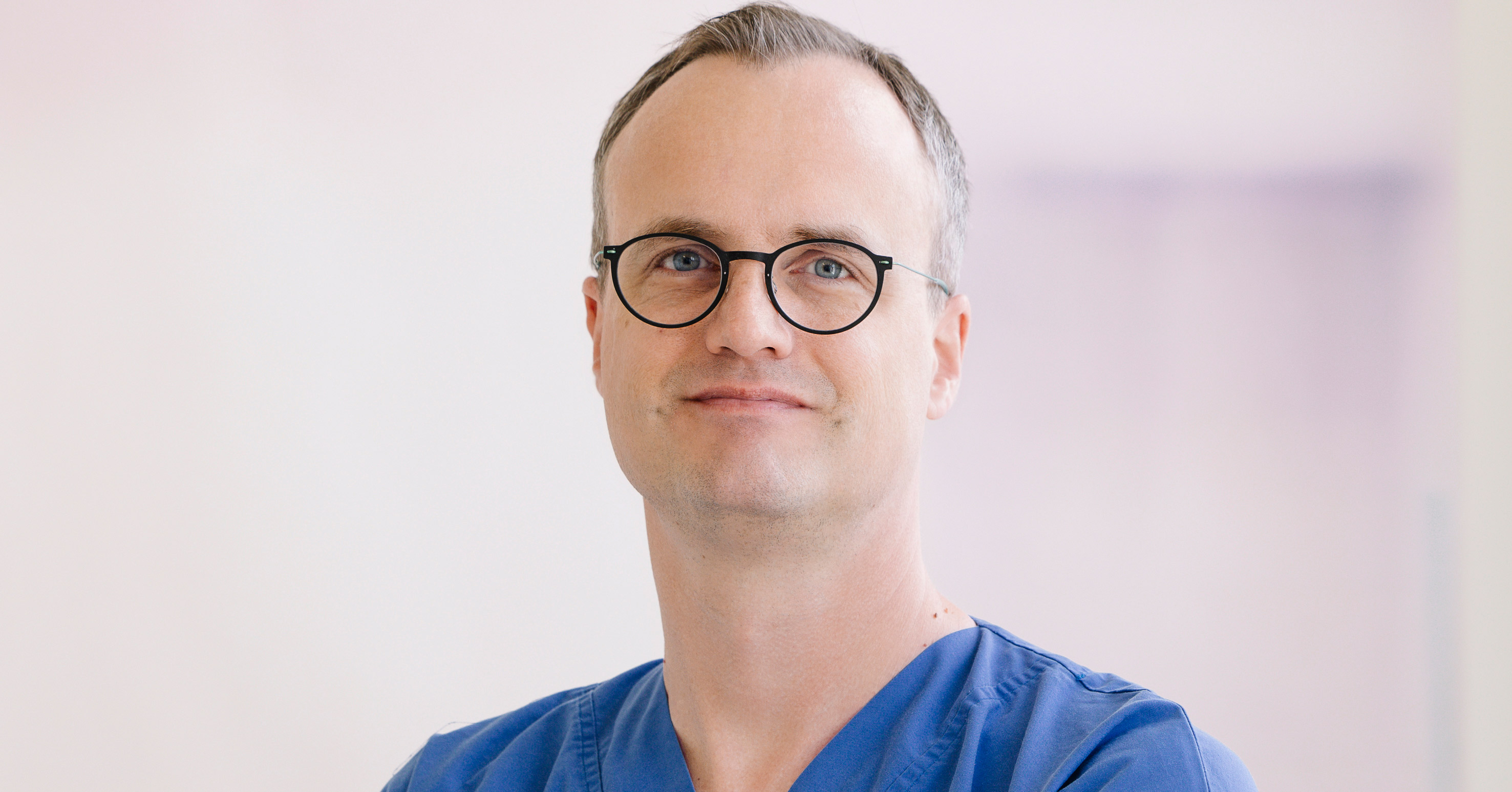 Arzt mit Brille und sehr kurzem Haar