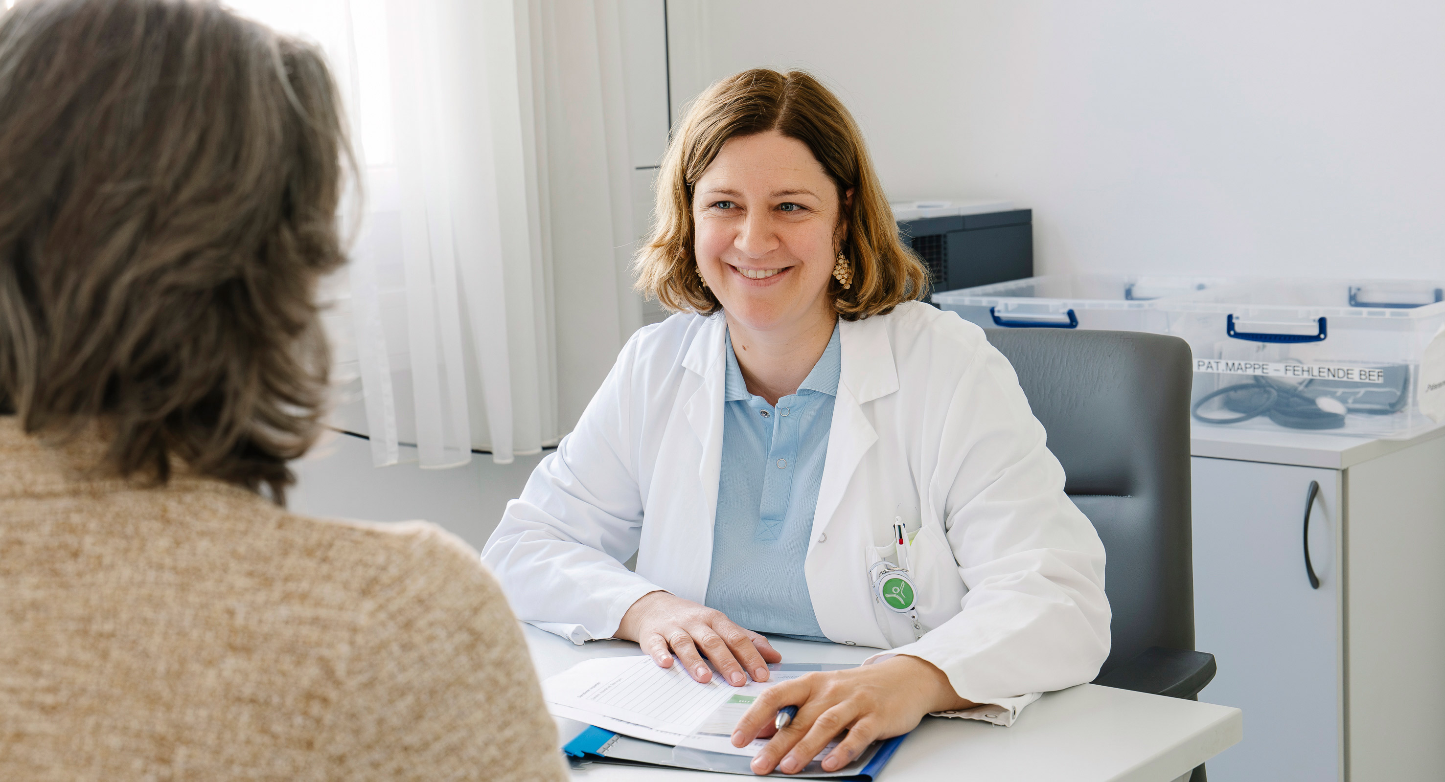 Eine Ärztin mit braunen Haaren beim Aufklärungsgespräch mit einer Patientin