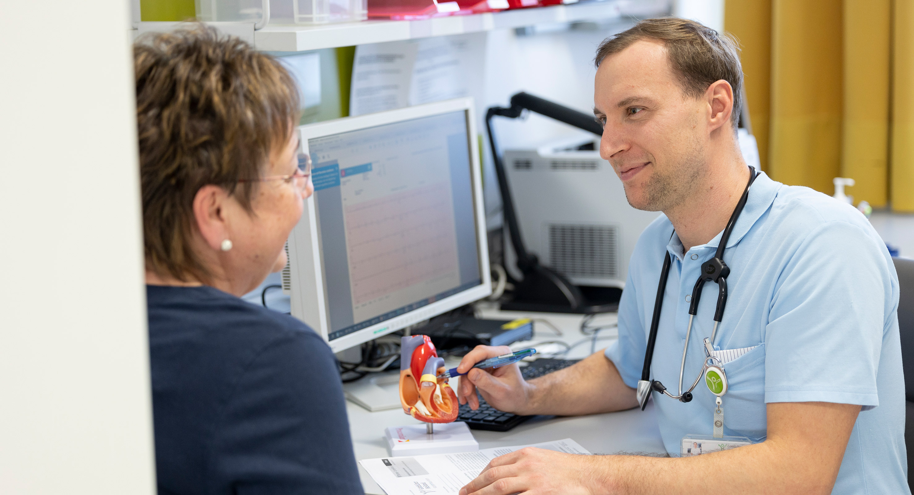 Ein Arzt bespricht ein EKG Befund mit einer Patientin