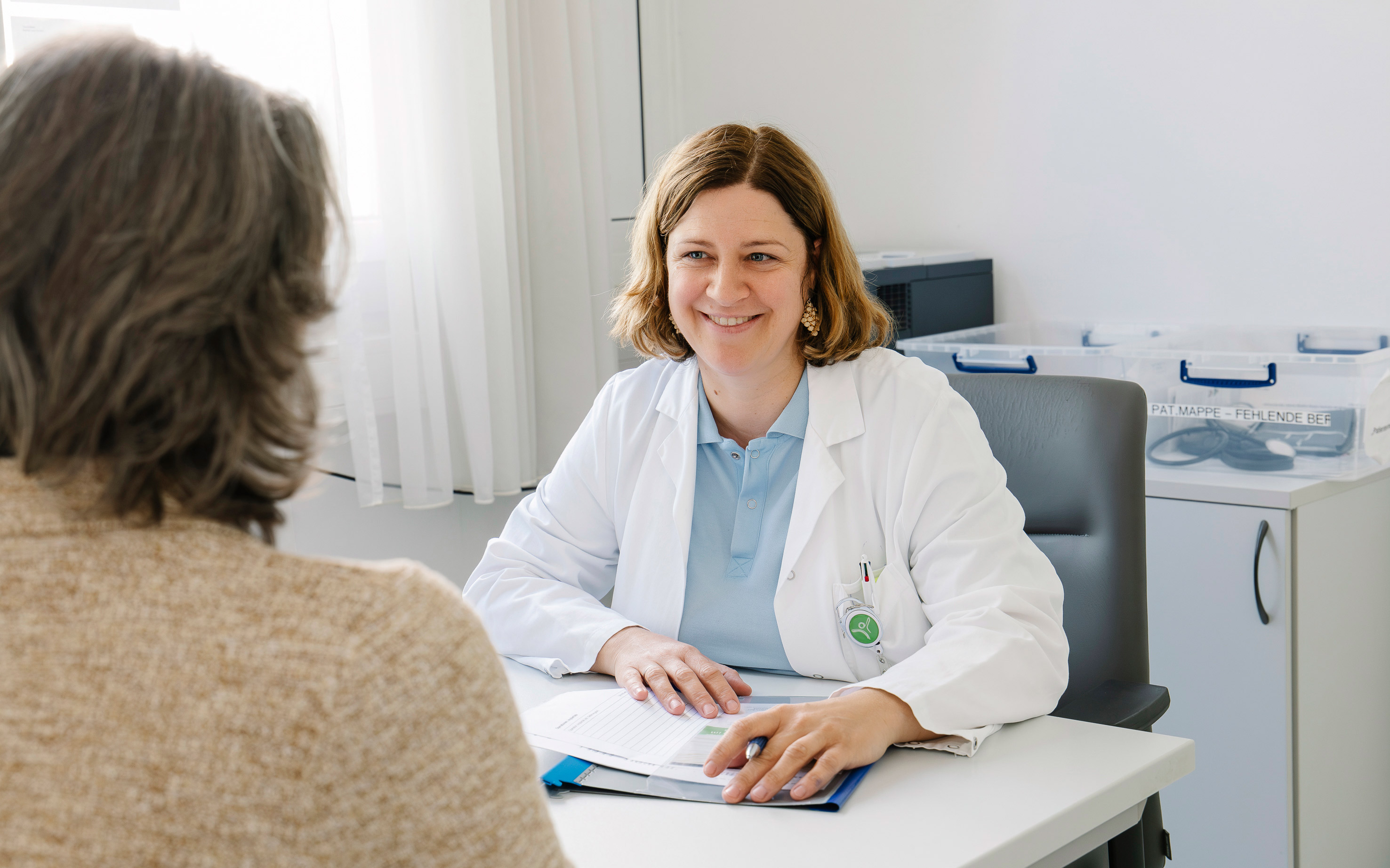 Eine Ärztin lächelt eine Patientin an bei einem Gespräch.