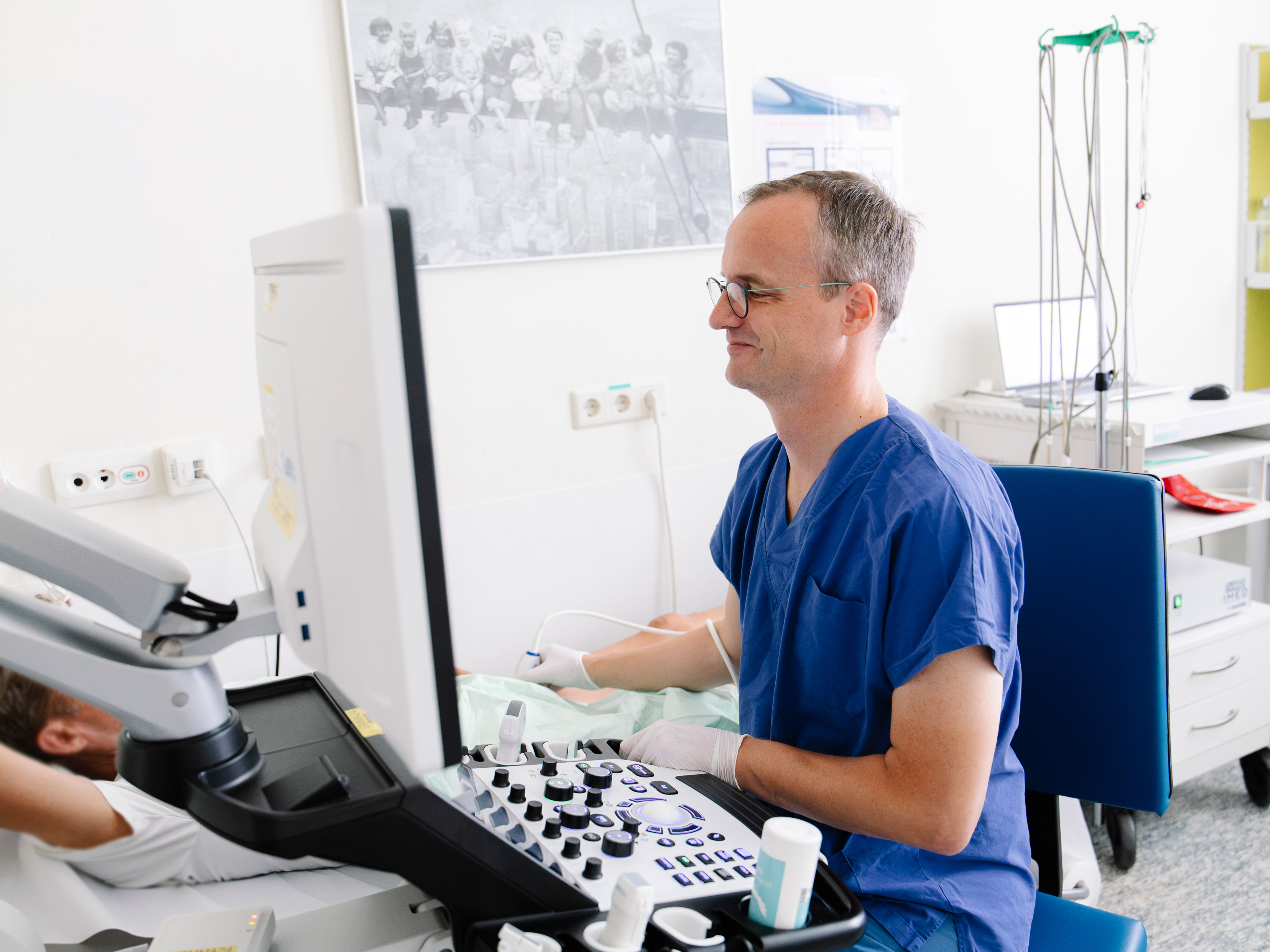 Ein Arzt untersucht bei einem Patienten die Beinarterien und Venen mittels Ultraschall