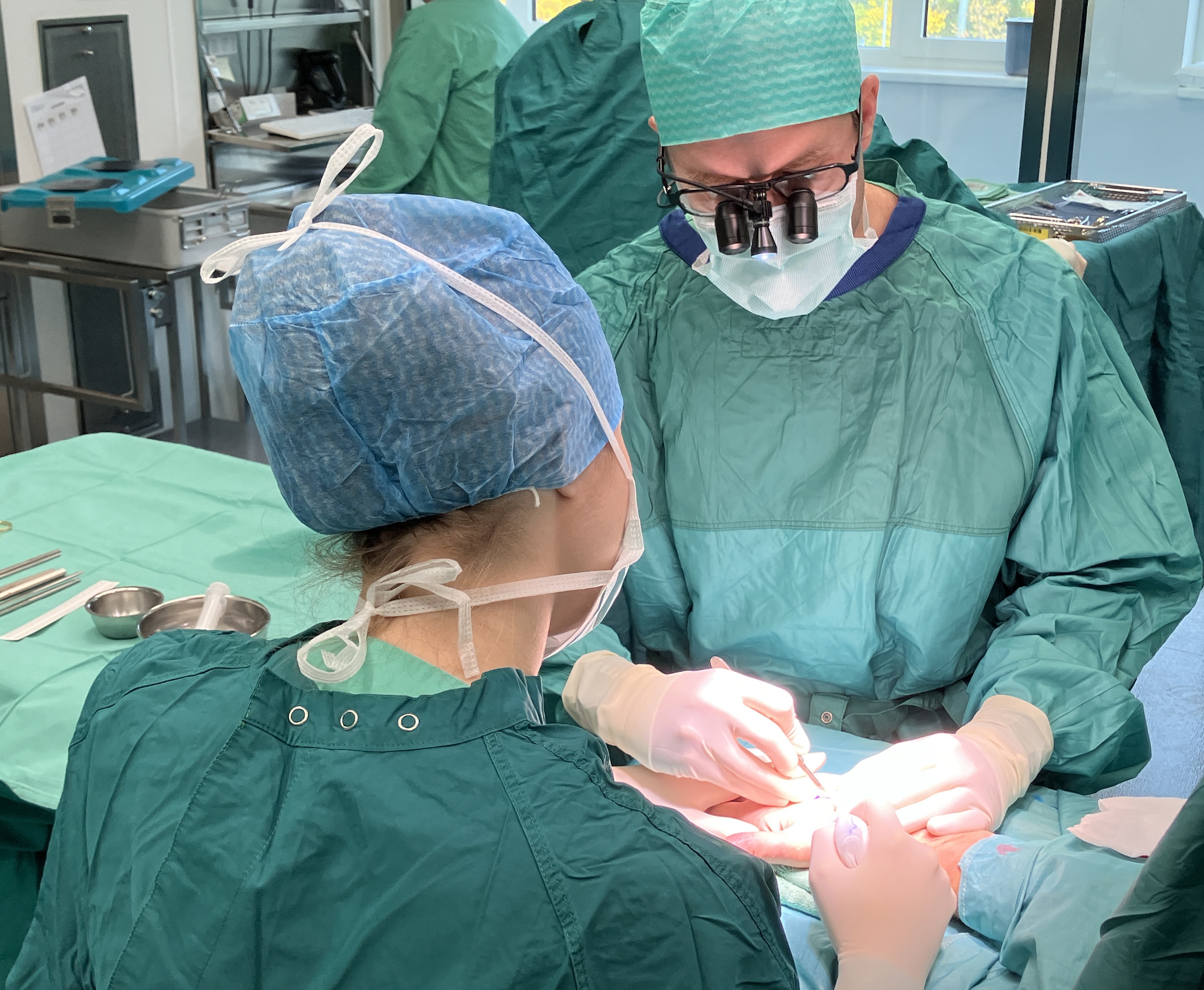 Zwei Chirurgen in OP-Kleidung führen konzentriert eine Operation eines Patienten durch.