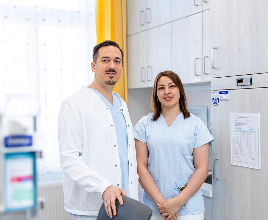 Ein Mann und eine Frau in Dienstkleidung stehen in einem Krankenhaus