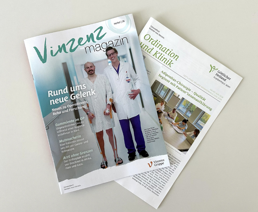 Zwei gedruckte Ausgaben des Newsletters 'Ordination und Klinik' des Krankenhauses Göttlicher Heiland Wien und eine Ausgabe des 'Vinzenz Magazins', die leicht versetzt auf einem weißen Tisch liegen.