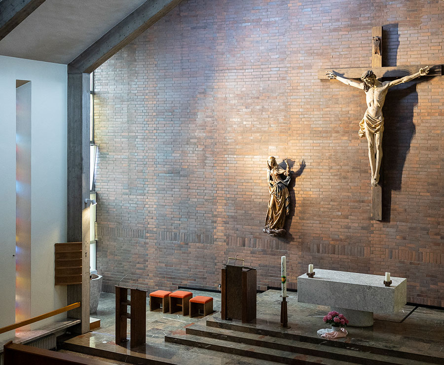 Blick in eine Kirche von hinten auf Jesus am Kreuz, den Altar und die ersten Sitzreihen.